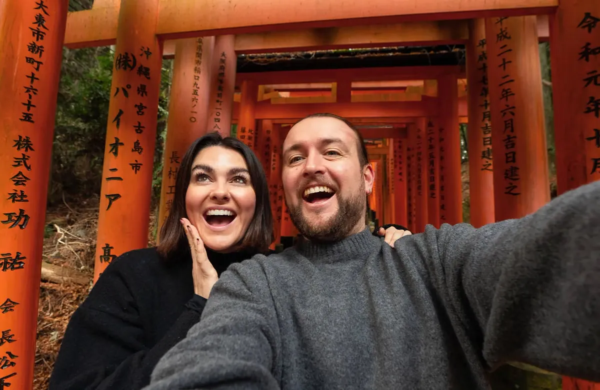 Twee reizigers maken een selfie bij de rode poorten in Kyoto, Japan